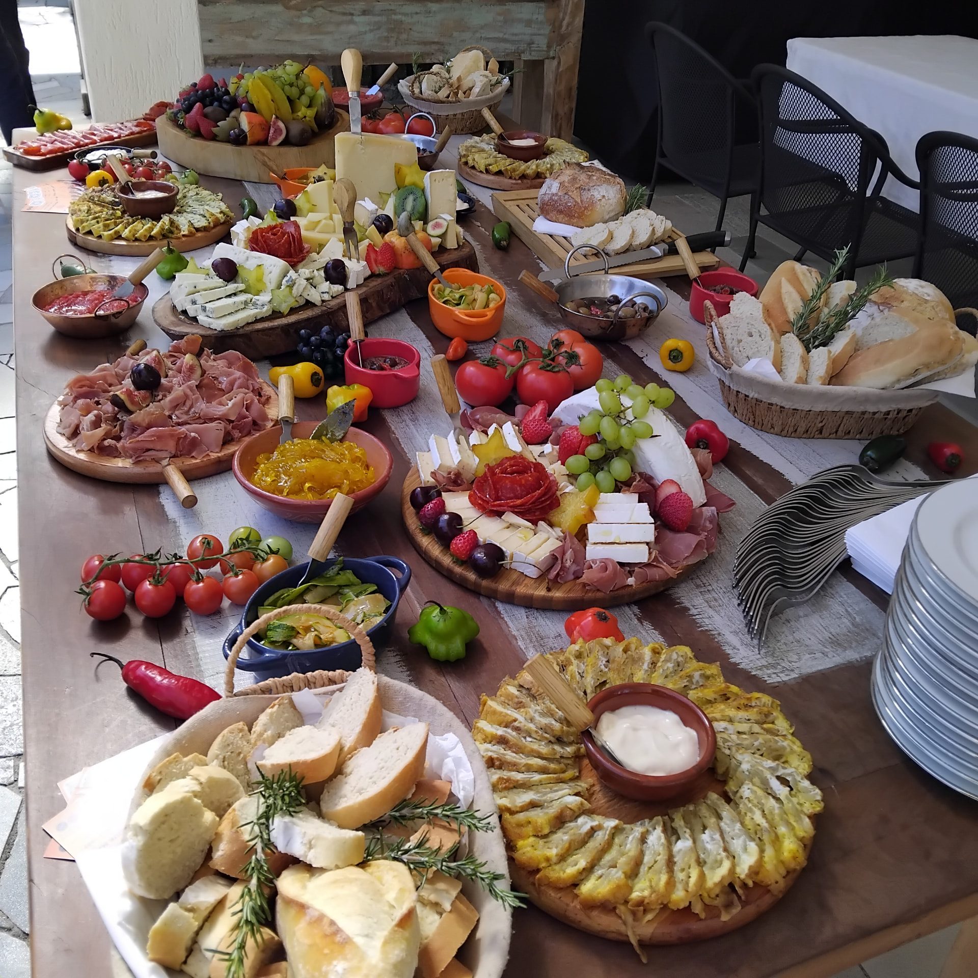 Mesa de entradas com queijos, embutidos, antepastos, pães e frutas