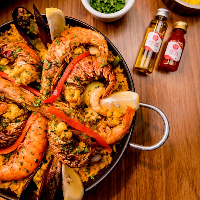 Paella de frutos do mar com camarões, mexilhões, pimentão e limões na paellera