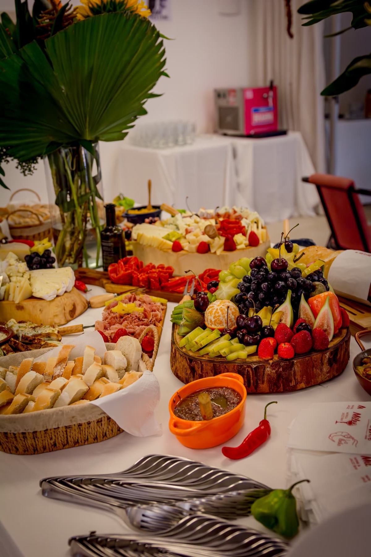 Ilha de entradas com frutas, molhos, cesta de pães e talheres de serviço