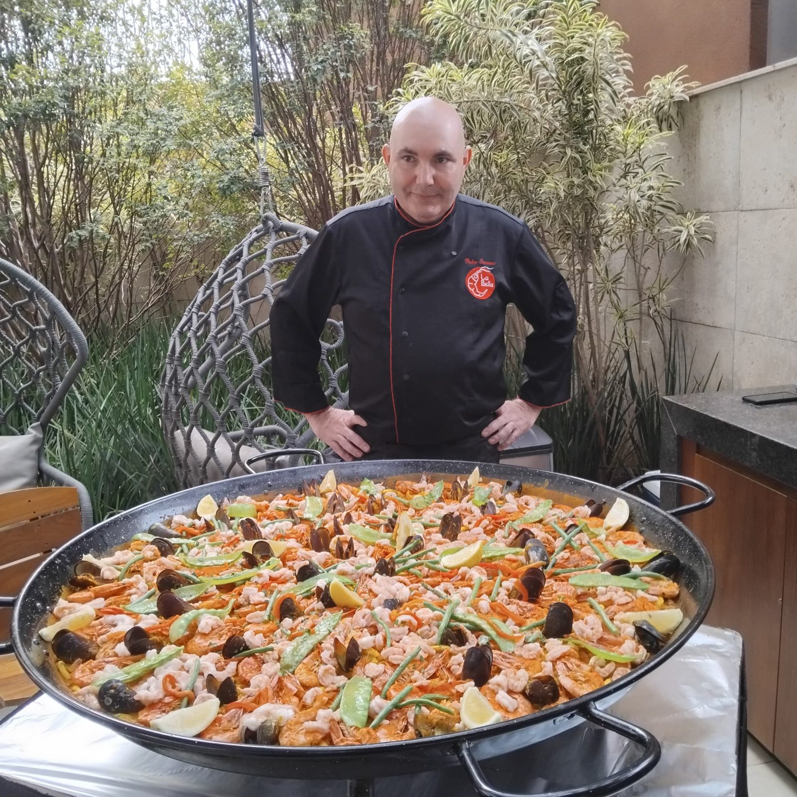 Chef Pedro Soriano atrás de uma paella gigante com camarões, mexilhões, vagens e limões